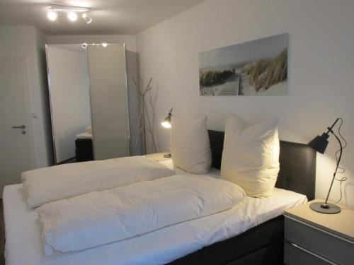 1 dormitorio con 1 cama con sábanas y almohadas blancas en de Glemfisk, barrierefrei, en Dorum-Neufeld