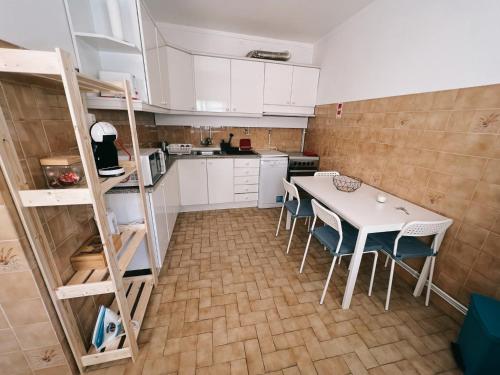 una cocina con mesa y sillas y una cocina con armarios blancos. en Apartamento da Fonte en Figueira da Foz