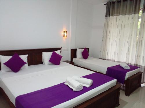 two beds in a room with purple and white at Cumini Resort in Anuradhapura