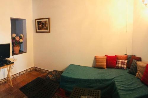uma sala de estar com uma cama com um cobertor verde em Casa Mora em Encinasola