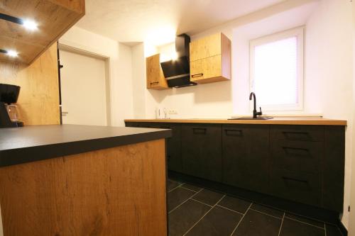 una cocina con encimera negra y fregadero en Almliesl MAIS-700 en Maishofen