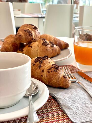 a table with two plates of bread and a cup of orange juice at Hotel Ducale in Rimini