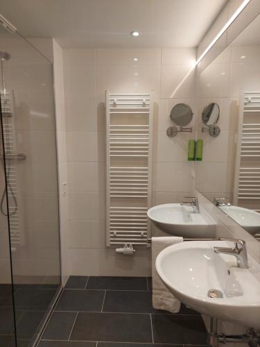 a bathroom with two sinks and a shower at Gartenhotel Altmannsdorf in Vienna