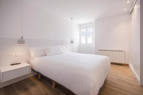 a white bedroom with a large white bed and a window at Apartamentos Lucio Rodinso in Castroverde