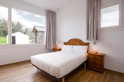 a bedroom with a white bed and two windows at Apartamentos Lucio Rodinso 