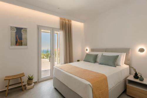 a white bedroom with a bed and a balcony at Summertime Villas in Argostoli