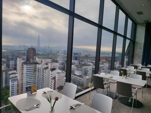 um restaurante com mesas brancas, cadeiras brancas e janelas em HOTEL in 9 Gangnam em Seul