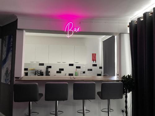 a kitchen with a bar with a pink neon sign at Coastal Comfort, Seaside Flat in Margate