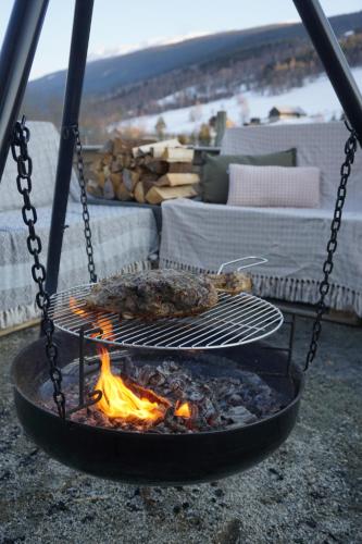 a grill with meat cooking over a fire at Heidal Gjestgiveri AS in Nedre Heidal