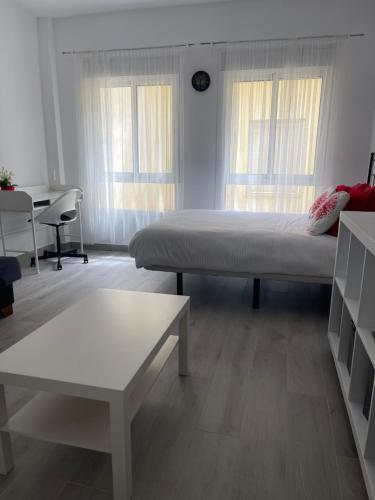 Schlafzimmer mit einem Bett, einem Tisch und Fenstern in der Unterkunft Victoria 68 SUITE in Málaga