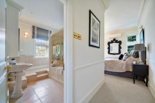 a bathroom with a sink and a bedroom with a bed at Finest Retreats - Elm Point House in London