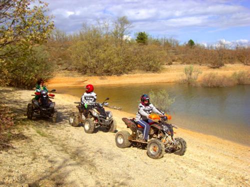 three people riding atvs on a dirt road near a river at Posada del Indiano in Cidones