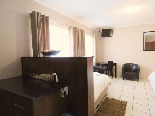a hotel room with a bed and a desk and a room at Andante Guesthouse Klerksdorp in Klerksdorp