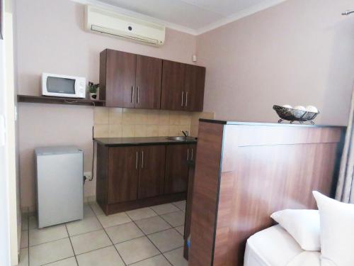 a kitchen with wooden cabinets and a white microwave at Andante Guesthouse Klerksdorp in Klerksdorp