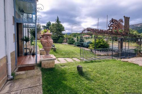 a house with a yard with a fence and a vase at Posada del Indiano in Cidones