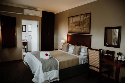 a hotel room with a bed with a towel on it at Alveston Manor Hotel in Middelburg