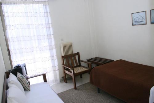 a bedroom with a bed and a chair and a window at Aparthotel Iliahtides in Amarinthos