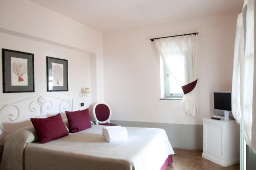 um quarto com uma cama com almofadas vermelhas e uma janela em La Salina Hotel Borgo Di Mare em Lingua