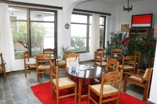 a dining room with a table and chairs and windows at Aparthotel Iliahtides in Amarynthos