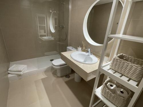 een badkamer met een wastafel, een toilet en een spiegel bij Casa Kalithea in La Herradura