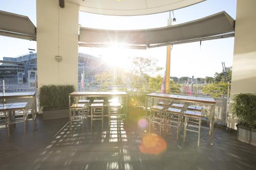a patio with tables and chairs and the sun shining at Novotel Sydney Olympic Park in Sydney