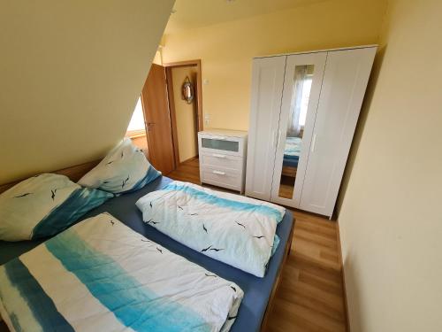 1 Schlafzimmer mit 2 Betten und einem Spiegel in der Unterkunft Ferienwohnung Leuchtturm am Sandstrand in Norden