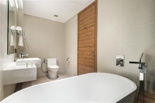a bathroom with a tub and a toilet and a sink at Flamingo Resort Cat Ba in Cat Ba