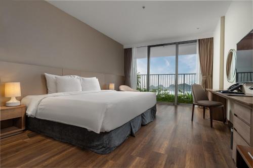 a hotel room with a large bed and a balcony at Flamingo Resort Cat Ba in Cat Ba