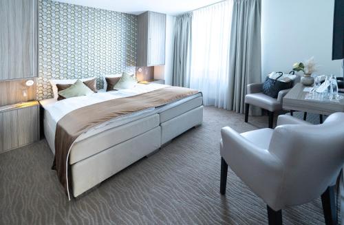 ein Hotelzimmer mit einem großen Bett und einem Schreibtisch in der Unterkunft Bernstein Salzlandcenter in Staßfurt