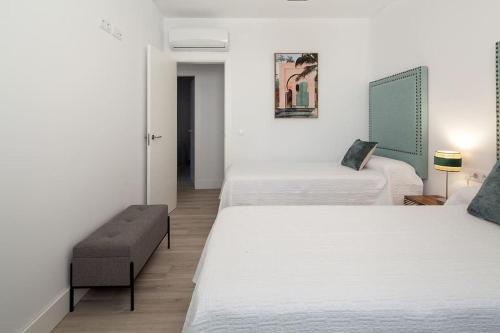 um quarto de hotel com duas camas e um banco em Stunning apartment in Nervion with parking em Sevilha