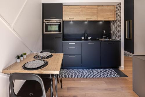 cocina con armarios negros y mesa de madera en Studio standing 3* Le Bernascon, en Aix-les-Bains