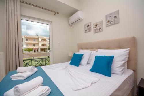 a bedroom with a bed with blue pillows and a window at Jasmine House Kissamos in Kissamos