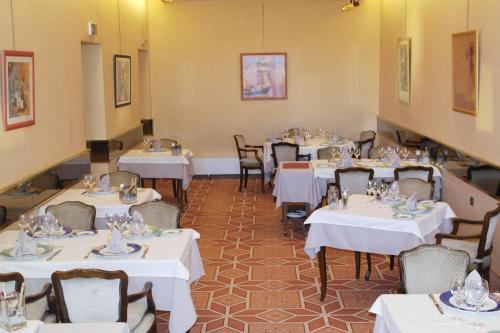 a dining room with white tables and chairs at Hôtel Restaurant Des Lys in Le Coteau