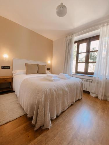 a bedroom with a large bed with white sheets and windows at Hotel Rural Candela y Plata in Puerto de Béjar