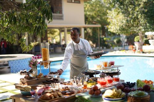 Un uomo in piedi di fronte a un buffet di cibo di Vatsalya Vihar - A Luxury Pool Villas Resort a Udaipur