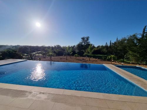 a large blue swimming pool with the moon in the background at Eco Lodge Villa das Alfarrobas com Piscina in Algoz