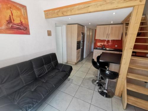 un salon avec un canapé noir et une cuisine dans l'établissement 5012 Green Village i6, au Cap d'Agde