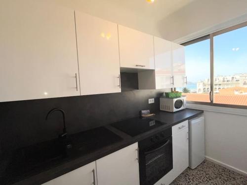 une cuisine avec des armoires blanches et un comptoir noir dans l'établissement Hendaye plage charmant studio 2pers avec grande terrasse vue mer, à Hendaye