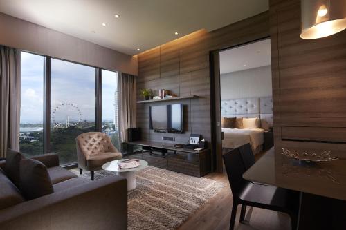 ein Wohnzimmer mit einem Bett und einem TV in einem Zimmer in der Unterkunft Pan Pacific Serviced Suites Beach Road, Singapore in Singapur