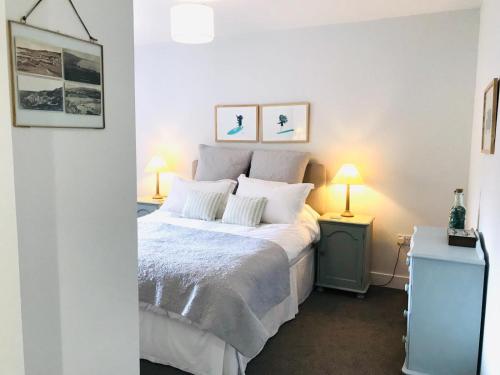 a bedroom with a bed with white sheets and two lamps at 5 Rockham - Luxury Apartment at Byron Woolacombe, only 4 minute walk to Woolacombe Beach! in Woolacombe