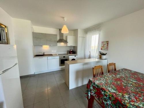 une cuisine avec des placards blancs et une table avec une nappe dans l'établissement Quiberon: Appartement 3 pièces, 65m², à deux pas des plages, terrasse, WIFI inclus - FR-1-478-25, à Quiberon