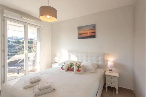een witte slaapkamer met een groot bed en een raam bij L8 Calm, panoramic Sea View withTerrace, Parking & AC in Saint-Laurent-du-Var