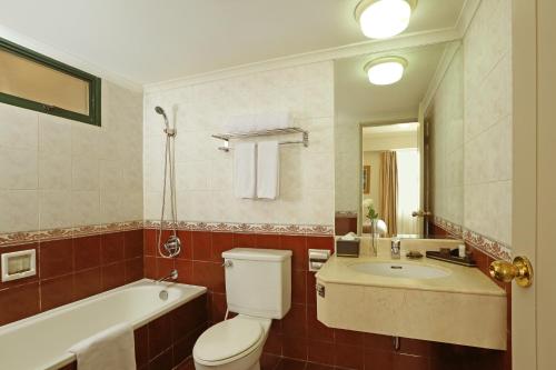 a bathroom with a toilet and a tub and a sink at Aryaduta Suite Semanggi in Jakarta