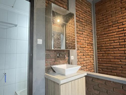 a bathroom with a sink and a brick wall at Panji Hostel in Sukasada