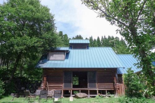 a log cabin with a blue roof and chairs at kaso Space kamiyama Log House 
