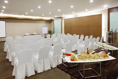 a room with white chairs and tables with food on them at Aryaduta Suite Semanggi in Jakarta
