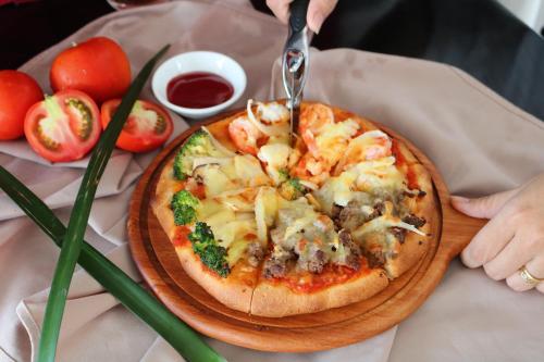 a pizza being cut on a wooden plate on a table at Hotel Del Luna Boutique in Da Nang