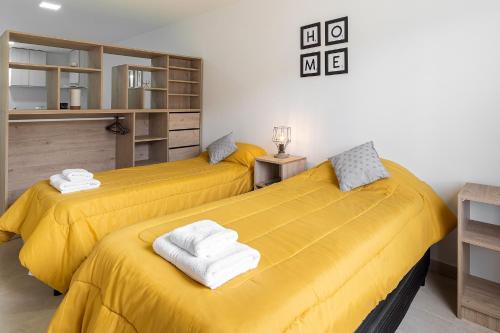 two beds in a room with yellow sheets and towels at Happy Guest Apart 50 in Ushuaia