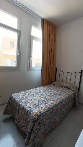 ein Bett in einem Schlafzimmer mit zwei Fenstern in der Unterkunft Apartamentos Boomerang II in Tamaduste