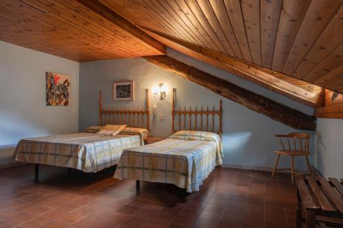 a bedroom with two beds and a wooden ceiling at Hotel Cardós in Ribera de Cardós